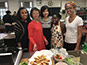 <p>From left: Health and Nutrition Club Vice President Naudia Jones; Professor Patricia Cai, a lecturer in kinesiology in the Department of Athletics; health and nutrition major Letao Wang; and health and nutrition major Patricia Pauyo surround Natasha Griffiths, a screenwriting student at the Feirstein Graduate School of Cinema. Griffiths cooked Jamaican ackee and saltfish with breadfruit for the event.</p>