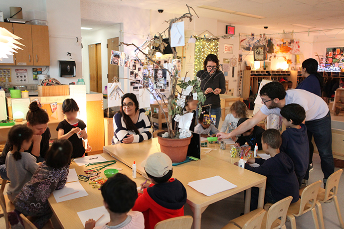 Kimberly Trapani ’15 ’18 (center), head teacher in the Early Childhood Center’s 'fours' class, sits with students as they work on a craft project. Photo by David Rozenblyum.
