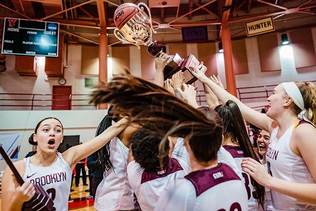The women Bulldogs raise the CUNYAC championship trophy for basketball. Photo: Denis Gostev