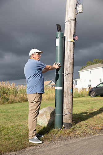 Brett Branco stands with a FloodNet sensor in Fort Hamilton. 