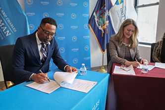 (Left to right) Guttman Community College President Larry Johnson and Brooklyn College President Michelle J. Anderson sign the articulation agreement that will help students interested in earth and environmental sciences transfer their credits more easily. 