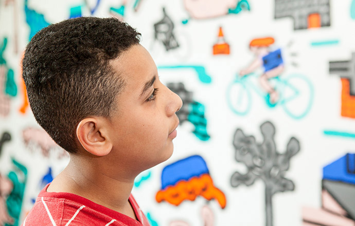 Ali looks at the PUMP mural on the wall at his school, admiring how it interpreted the poetry he and his classmates wrote. Photo by Craig Stokle.